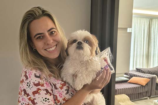 Profissional veterinária segurando um cachorro durante coleta domiciliar